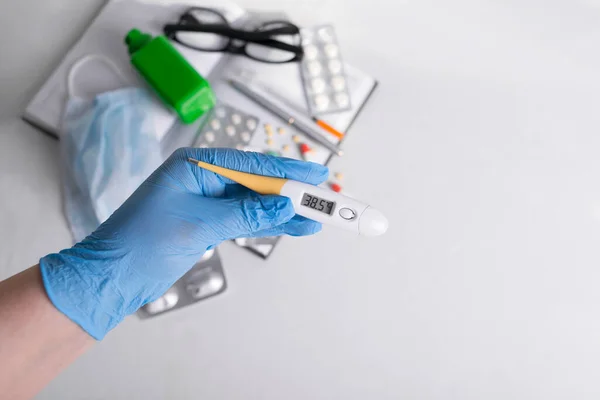 İlaçlar ve termometre masanın üstünde, düz yerde. Vitaminler, besin takviyeleri, insülin şırıngası, doktor gözlükleri. Yüksek sıcaklıkta termometre. Tıbbi maske ve antiseptik. 