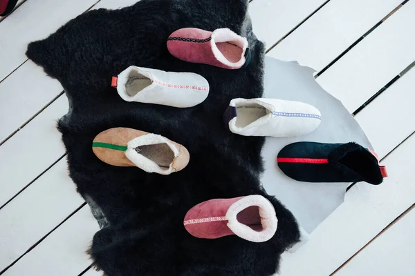 El yapımı sıcak yün terlikler. Koyun derisi terliklerin farklı renkleri. Doğal yün terlikler ve dayanıklı, kaymaz taban.