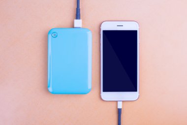 Akıllı telefonlar ve şarj. Masaya turuncu arka plan