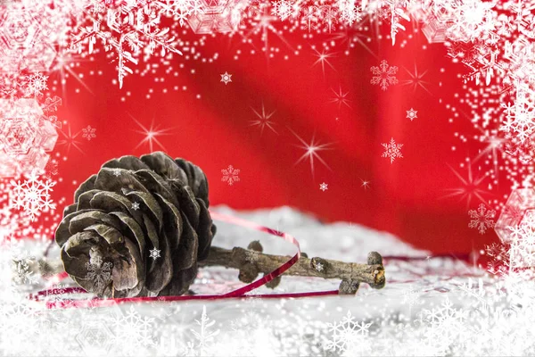 Un juguete de Navidad, un cono de pino sobre un fondo rojo con copos de nieve a su alrededor —  Fotos de Stock