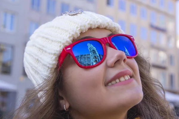 Retrato de una joven alegre de cerca. El nuevo ayuntamiento de Munich se refleja en las gafas de sol rojas . — Foto de Stock