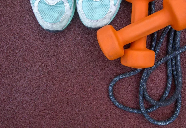 Scarpe da corsa, manubri, corda per saltare - accessori per il fitness su una superficie in gomma sportiva. Copia spazio per testo. Vista dall'alto — Foto Stock