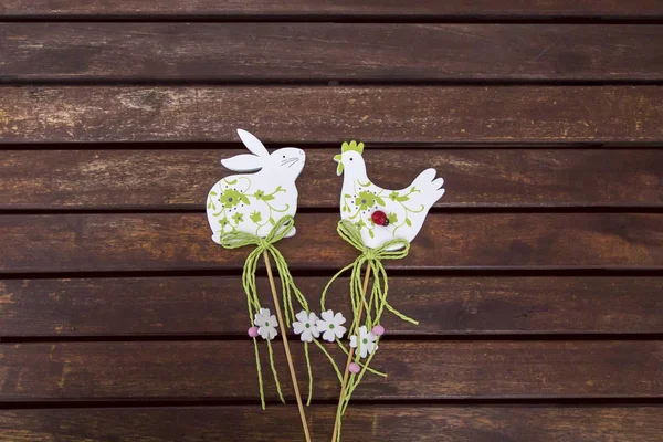 Easter toys white rabbit and chicken / rooster on a brown wooden table, pattern, place for text