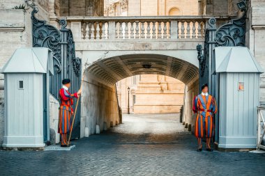 Two Papal Swiss Guard in uniform standing with a halberd at the entrance of Saint Peter's Basilica, Vatican city, Rome, Italy clipart