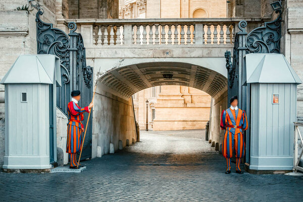 Two Papal Swiss Guard in uniform standing with a halberd at the entrance of Saint Peter's Basilica, Vatican city, Rome, Italy