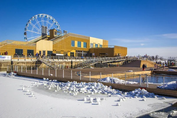 Allas Sea Pool- spa & wellness hub with large pools with sea warm water and saunas for relax in South Harbour of Helsinki, in winter sunny day, Ferris wheel in background, Finland.