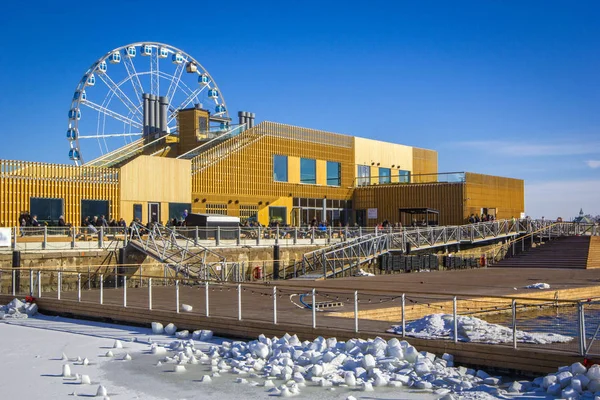 Allas Sea Pool- spa & wellness hub with large pools with sea warm water and saunas for relax in South Harbour of Helsinki, in winter sunny day, Ferris wheel in background, Finland.