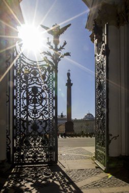 Hermitage Müzesi Ferforje kapıları ile kemer İskenderiyeli sütundan ve kapı yaprak, gölgesinden güneş aydınlatmak giriş Hermitage, St. Petersburg, Rusya Federasyonu için ışınlarının manzaralı Palace Square