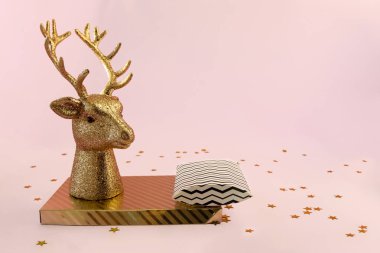 Xmas kompozisyonu minimal tarzda - altın üzerinde altın geyik kafası, çizgili kutu pembe arka planda duruyor Yeni yıl ışıkları, kopyalama alanı
