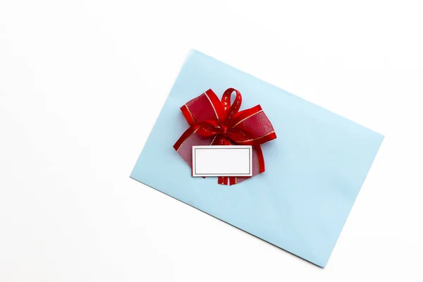 赤いリボンの弓を持つ空白の紙の青い封筒 白い背景に郵便のための手紙 フラットレイアウト トップビュー 概念郵便事業又はグリーティングカード — ストック写真
