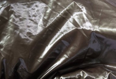 Gümüş renkli parlak metal arka planda buruşmuş. Parlak gri renkli, düz olmayan yüzeyli ince folyo desenli..