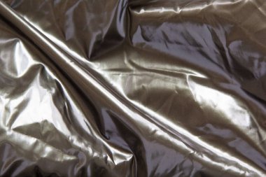 Gümüş renkli parlak metal arka planda buruşmuş. Parlak gri renkli, düz olmayan yüzeyli ince folyo desenli..