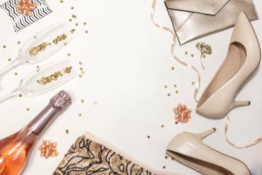 Set of women accessories party creative composition: shoes, decorations, glasses and bottle of champagne, clothes,  gifts, confetti on white background. Top view, flat lay, copy space