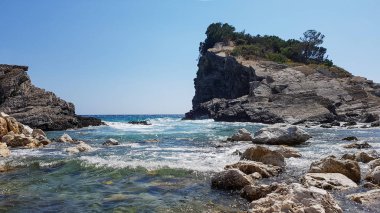 Panoramik manzaralı açık gök mavi su ve katmanlı kayalar, ile çakıl plaj güzel Akdeniz Adriyatik Denizi kıyısında, Karadağ