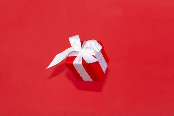 赤い背景に白いサテンリボン弓飛んで赤いギフトボックス クリスマス休暇 誕生日 バレンタイン ショッピング 販売のための最小限の概念 — ストック写真