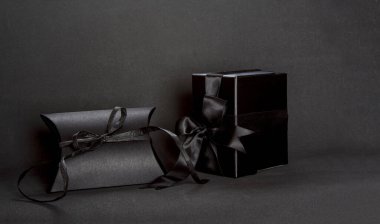 Two black gift boxes with black ribbon bow on dark background, copy space. Valentine's day, birthday romantic concept, greeting card.
