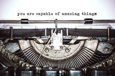Old vintage typewriter, retro machine with white sheet of paper and typed text 