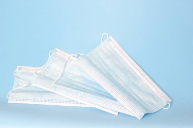 Mavi arka planda lastik kulaklıklı tıbbi maskeler. Bakteri ve virüsten korunma kavramı
