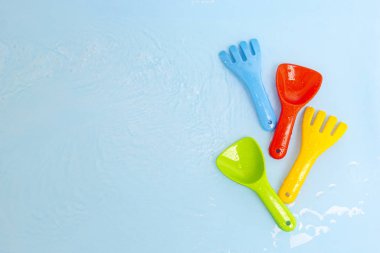 Mavi su yüzeyi üzerinde parlak renkli çocuk su oyuncakları, üst manzara, kopyalama alanı