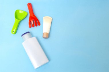 Güneş kremi, çocukların cildine güneş kremi sürerken mavi su yüzeyi üzerinde renkli su oyuncakları, üst manzara. Ultraviyole koruma ürünü kavramı, yaz çocukları kozmetik ürünleri.