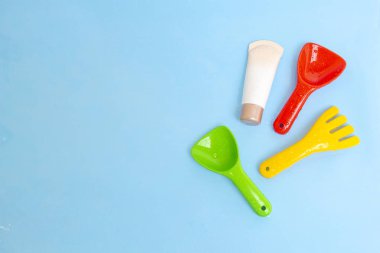 Güneş kremi, çocukların cildine güneş kremi sürerken mavi su yüzeyi üzerinde renkli su oyuncakları, üst manzara. Ultraviyole koruma ürünü kavramı, yaz çocukları kozmetik ürünleri.