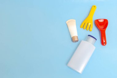 Güneş kremi, çocukların cildine güneş kremi sürerken mavi su yüzeyi üzerinde renkli su oyuncakları, üst manzara. Ultraviyole koruma ürünü kavramı, yaz çocukları kozmetik ürünleri.
