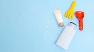 Güneş kremi, çocukların cildine güneş kremi sürerken mavi su yüzeyi üzerinde renkli su oyuncakları, üst manzara. Ultraviyole koruma ürünü kavramı, yaz çocukları kozmetik ürünleri.