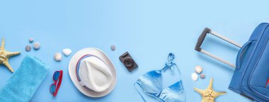 Seyahat aksesuarlarını mavi arkaplana ayarla. Plaj şapkası, havlu, bavul, güneş gözlüğü, denizyıldızı, kamera, kadın yaz tatili için deniz kabuğu. Banner moda konsepti, top view, flat lay