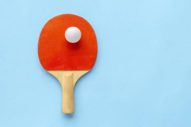 Masa tenisi için kırmızı raket, mavi arka planda beyaz top. Masa tenisi spor ekipmanları minimum düzeyde. Düz konum, üst görünüm, kopyalama alanı