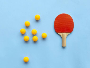 Masa tenisi için kırmızı raket ve mavi arka planda sarı toplar. Masa tenisi spor ekipmanları minimum düzeyde. Düz konum, üst görünüm, kopyalama alanı