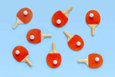 Masa tenisi için kırmızı raketler, mavi arka planda beyaz toplar. Masa tenisi spor ekipmanları minimum düzeyde. Düz konum, üst görünüm, kopyalama alanı