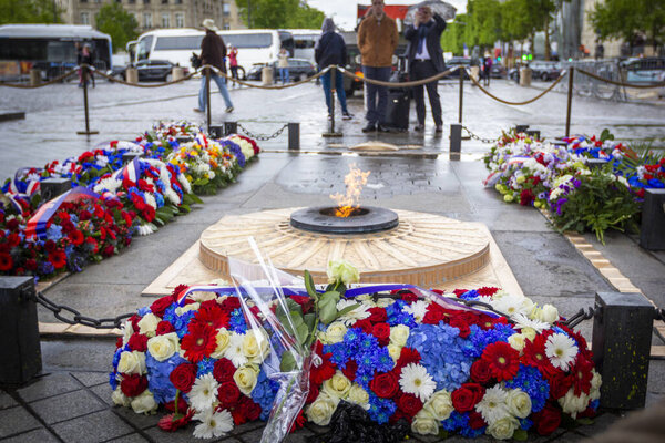 PARIS, FRANCE - MAY 8, 2019: Flowers and eternal flame near Arc de Triomphe in honor of victory over fascism in World War II on Place de Gaulle in Paris, France