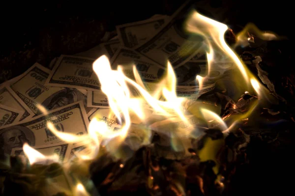 One hundred dollar banknotes burning in fire. Dollars burning.
