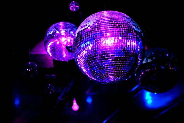 Mavi ve mor ışıklı bir gece kulübünde disko topu. Yansımalı ve kirişli ayna topu.