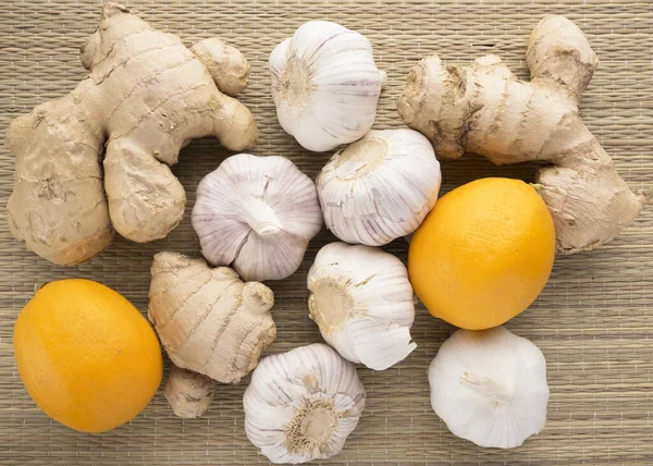 Ginger, garlic and lemons on a woven background. Healthy organic products.