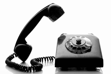Siyah ve beyaz telefonları olan klasik bir sabit hat. Retro tarzı bir telefon ve sarmalanmış bir kablo. Metin için kopyala-yapıştır alanı olan beyaz arkaplan üzerindeki eski telefon.