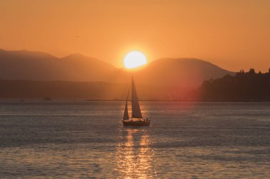 Silüet içinde uzak bir yelkenli, Puget Sound tepelerinin ardında güneş batıyor..