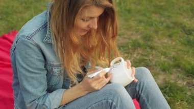 Bir desen boya ile bir tüp üzerinde beyaz bir kupa çizimi eller Close-up. Kırmızı ekose akşamları oturan kız boyalar süsleme.