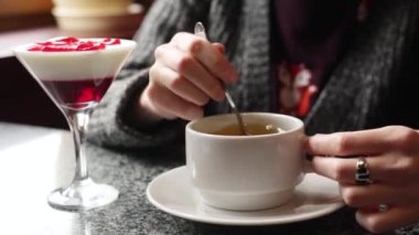 Kız beyaz bir bardağa şeker kıpırdanırken. Eller yukarı bir fincan çay ile.