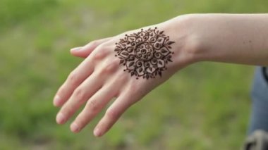 Çiçek mehndi dövme olan beyaz kadın eli.