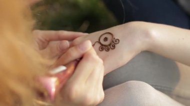 Genç kadın çiçek mehendi kına kullanarak bir el yapımı.