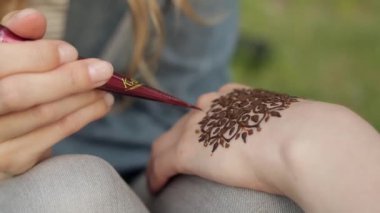 Genç kadın çiçek mehendi kına kullanarak bir el yapımı.