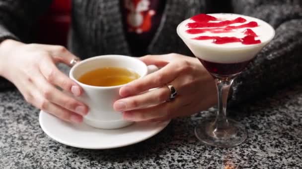 Pretty girl warms her hands, holding a cup of hot black or green tea. — Stock Video