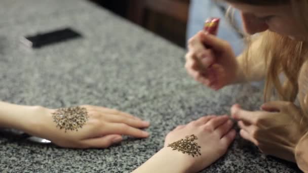 Mujer haciendo mehendi floral en una mano con henna en una mesa . — Vídeos de Stock