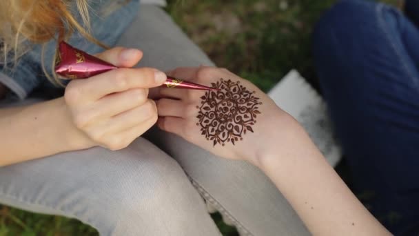 Giovane donna che fa mehendi floreali su una mano con hennè . — Video Stock