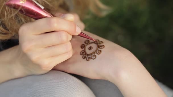 Mujer joven haciendo mehendi floral en una mano usando henna . — Vídeo de stock