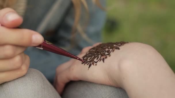 Mujer joven haciendo mehendi floral en una mano usando henna . — Vídeos de Stock