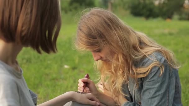 Ung kvinna att göra blommig mehendi på en hand med henna. — Stockvideo