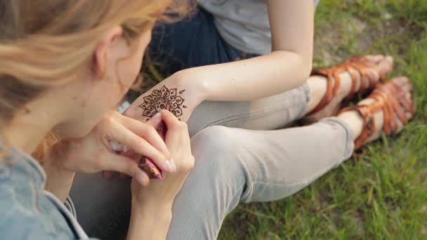 Ung kvinna att göra blommig mehendi på en hand med henna. — Stockvideo