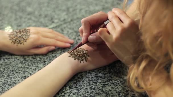 Mujer haciendo mehendi floral en una mano con henna en una mesa . — Vídeos de Stock